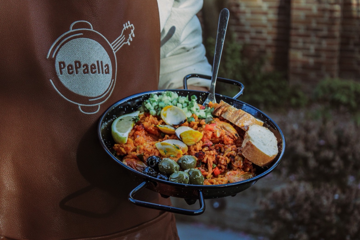 Portie paella in een emaille pannetje met brood en olijven