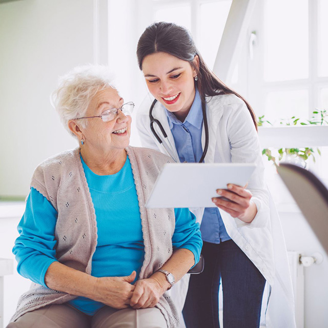A heath care worker showing something on a tablet to a patient