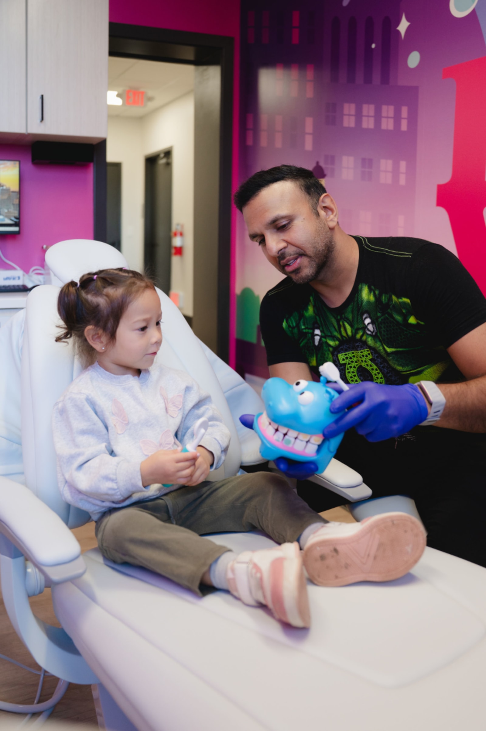 Dentist showing a child a colorful dental model during a procedure explanation