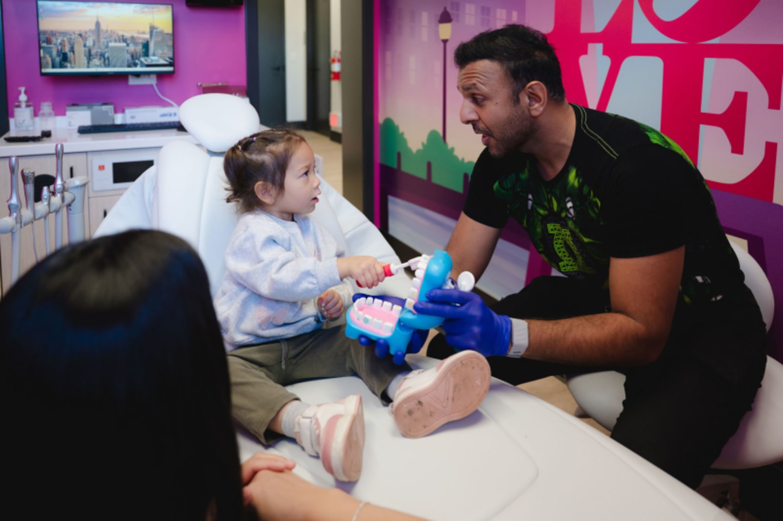 Dentist explaining procedure to young child in colorful treatment room