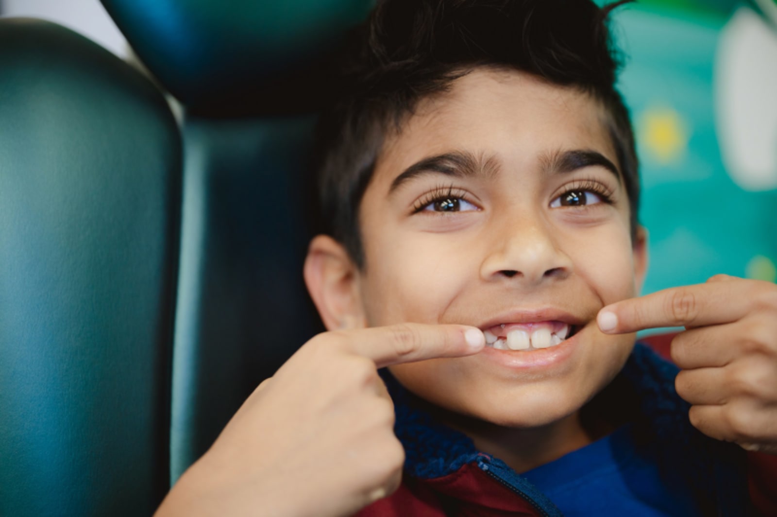 Young boy smiling with hands on face, showing comfort and confidence at the dental office