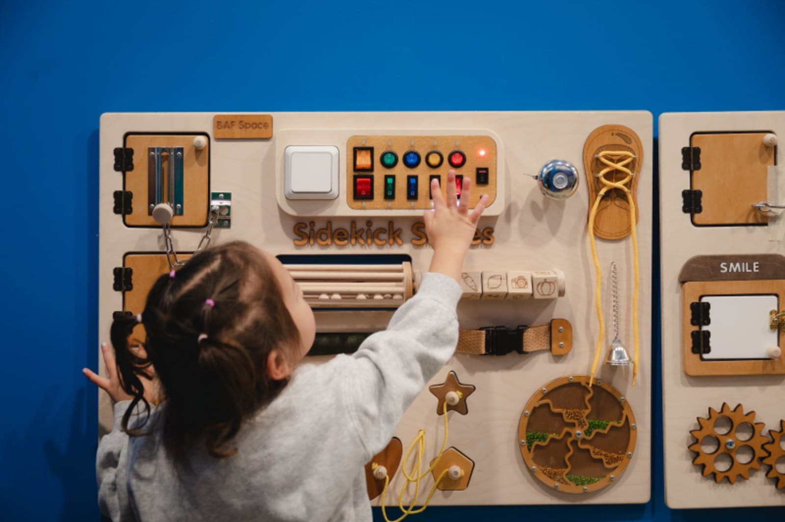 Child interacting with educational dental learning model on blue wall