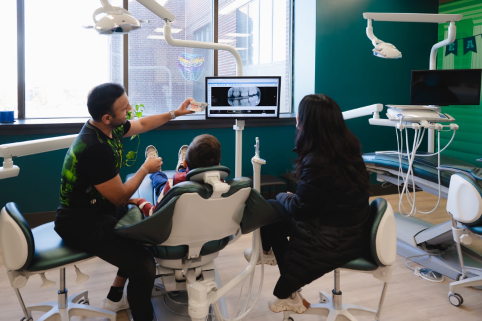 Dentist and young patient interacting together in treatment room during dental exam