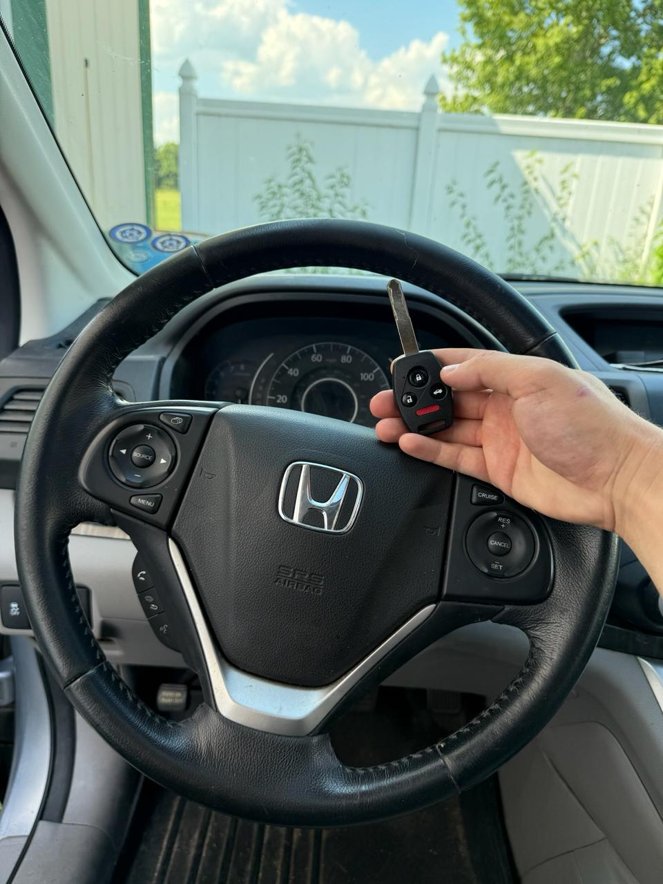 Locksmith holding programmed Honda car key in front of steering wheel