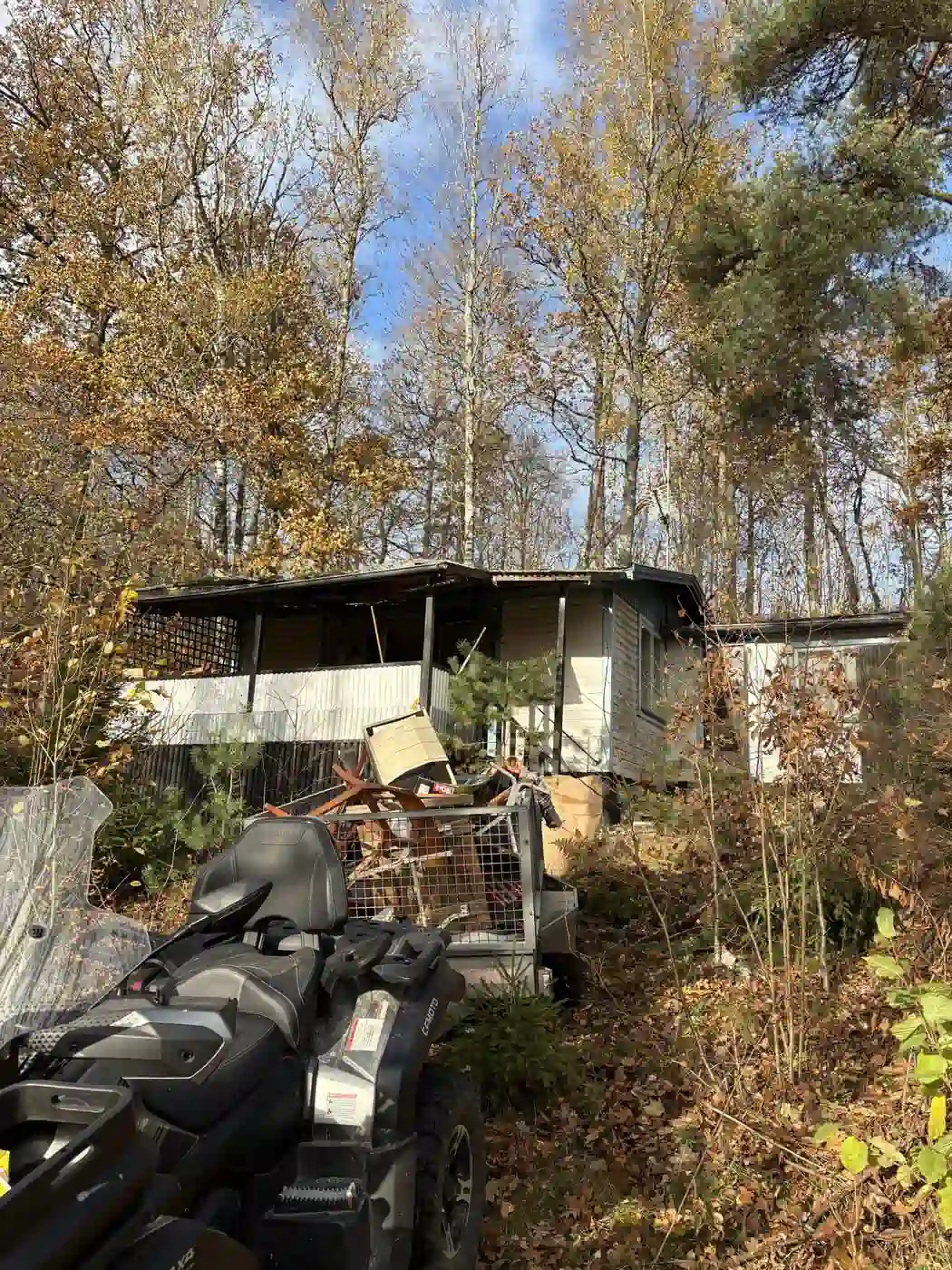 Fyrhjuling med kärra vid bortforsling från en fastighet i skogen
