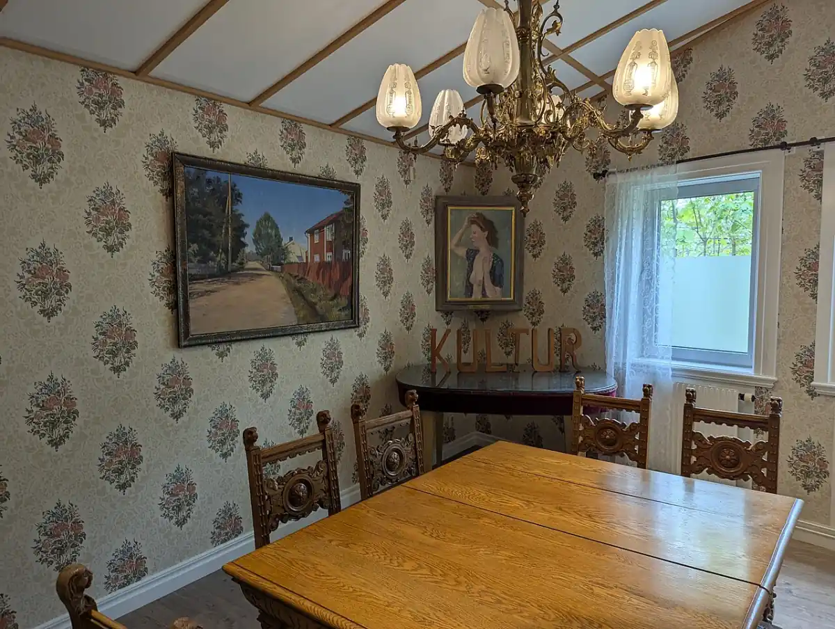 Äldre interiör i Kisa med träbord och tapeter