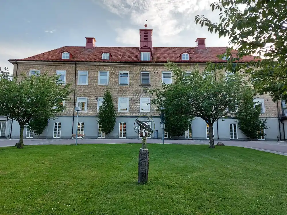 Äldre byggnad i Mölndal med gräsmatta och staty