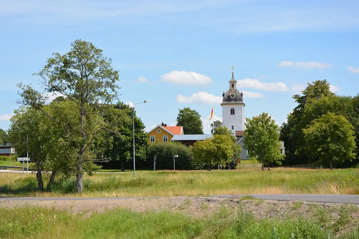Kyrka i Rottne sedd över fält och träd