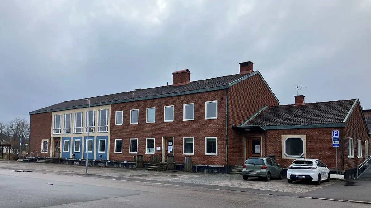 Tegelbyggnad i Rödeby med parkering och väg