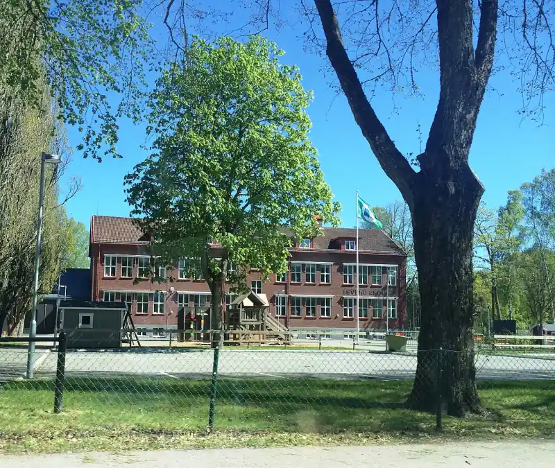 Offentlig byggnad i Vara bakom träd och gräsytor