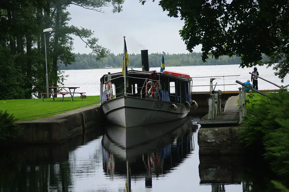Kanalbåt vid sluss i Åby med vatten och grönska