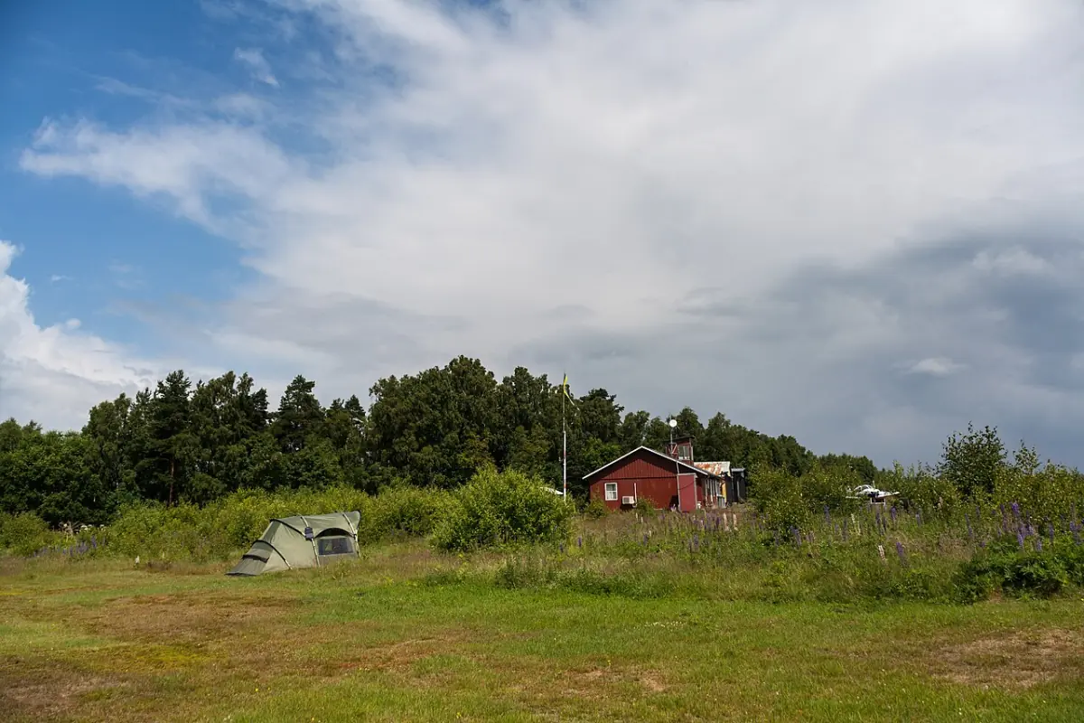 Öppen mark i Älmhult med röd stuga och skogsbryn