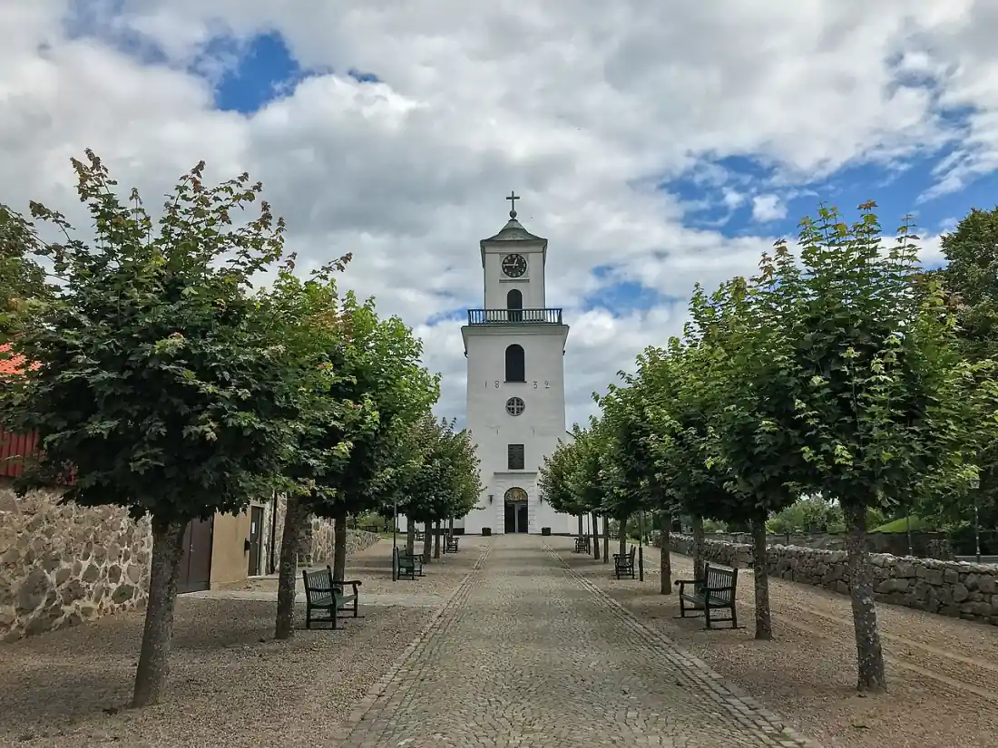 Kyrka i Jämshög sedd genom allé och stenmur