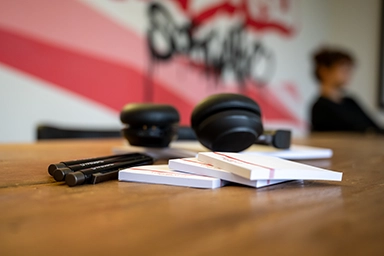 Kopfhörer, die auf einem Papierblock auf einem Tisch liegen.