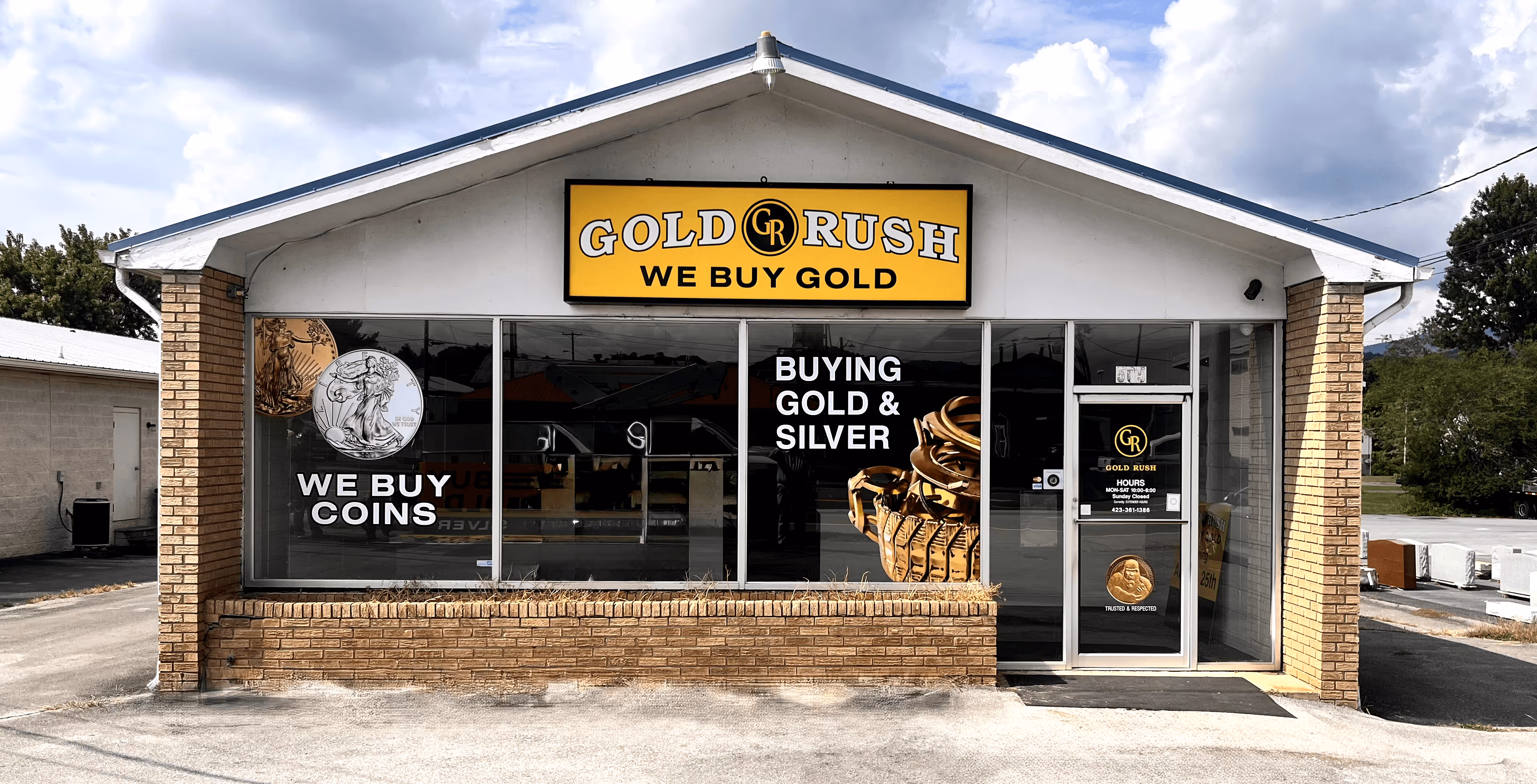 Front view of Gold Rush shop with yellow sign reading 'WE BUY GOLD', window ads for buying coins and gold & silver, and glass door.