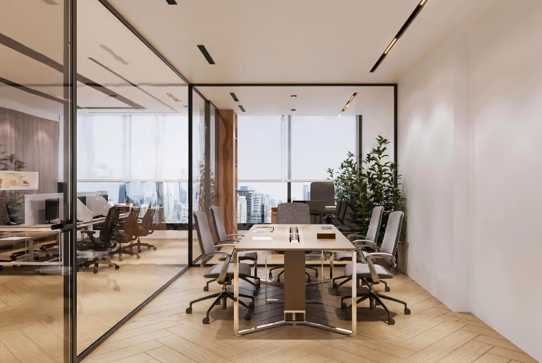 Modern office space with wooden desks, desktop computers, black mesh chairs, and large windows overlooking city buildings.