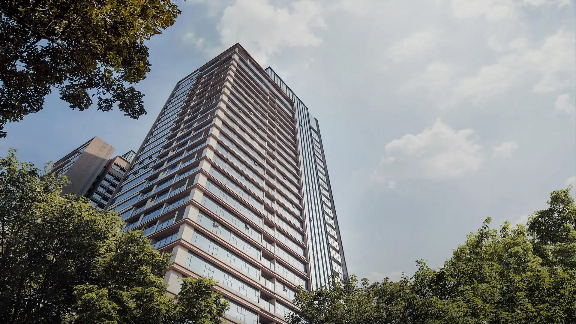 háp căn hộ cao cấp The Marq Saigon nhìn từ dưới lên với bầu trời xanh và hàng cây xanh mát