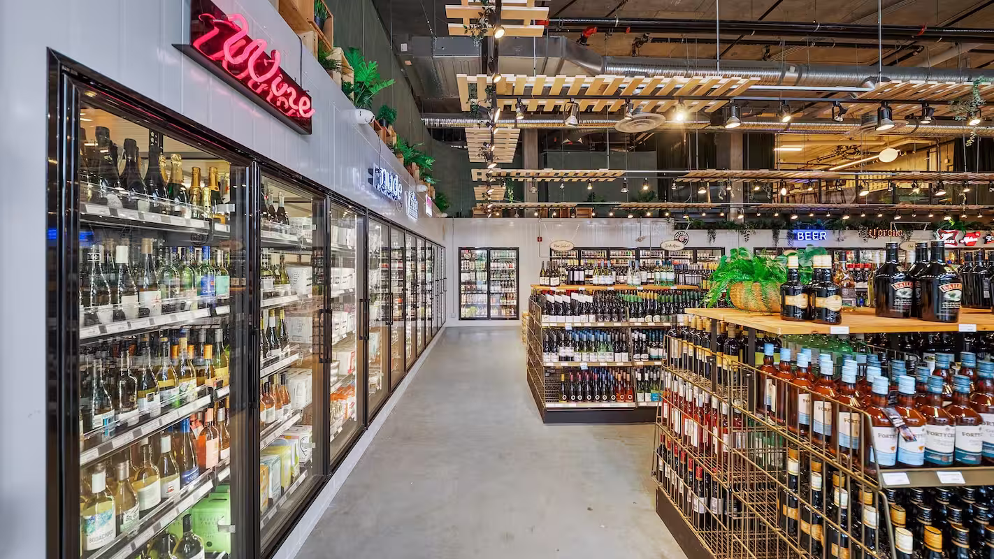 Interior of a modern liquor store with shelves and coolers filled with bottles of wine and spirits.