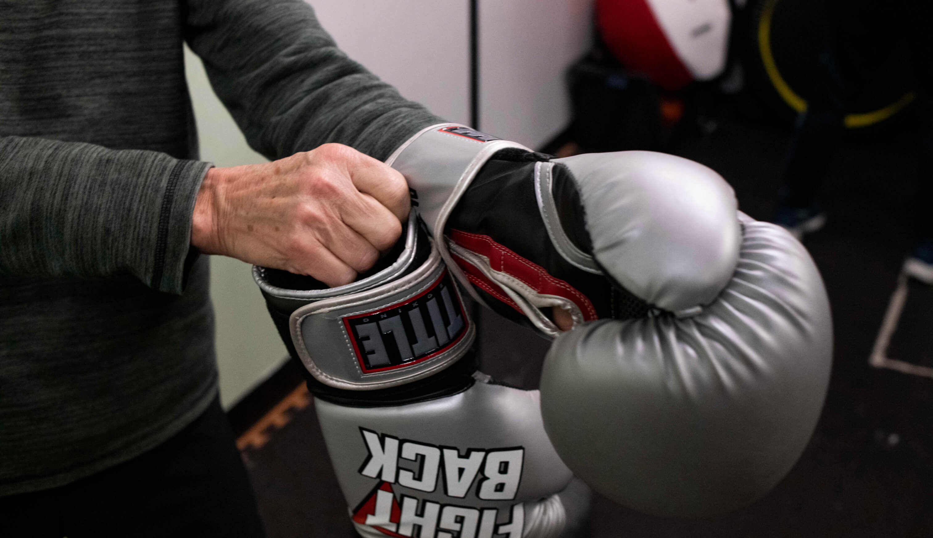 Hands putting on a pair of boxing gloves. 