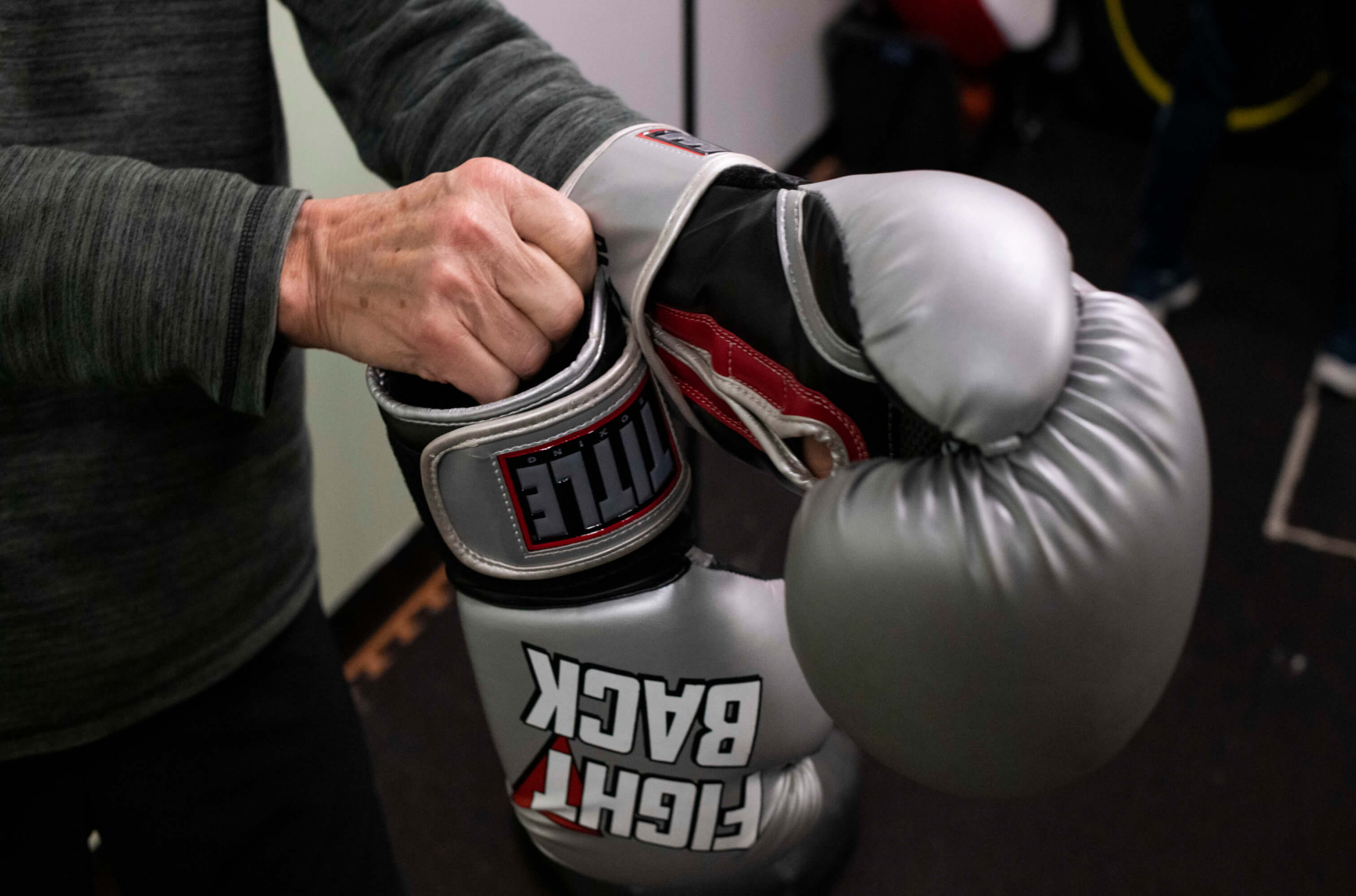 Hands putting on a pair of boxing gloves. 