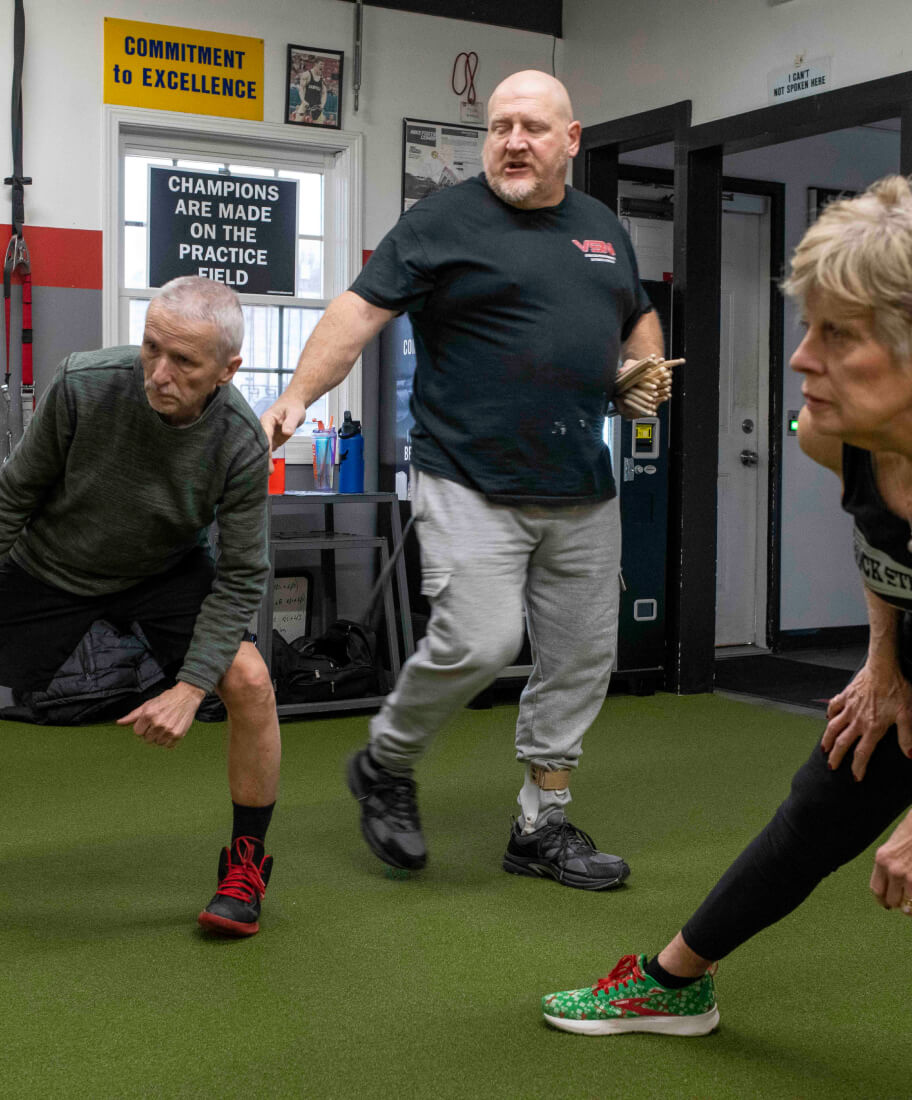 Three people stretching on a green mat. 