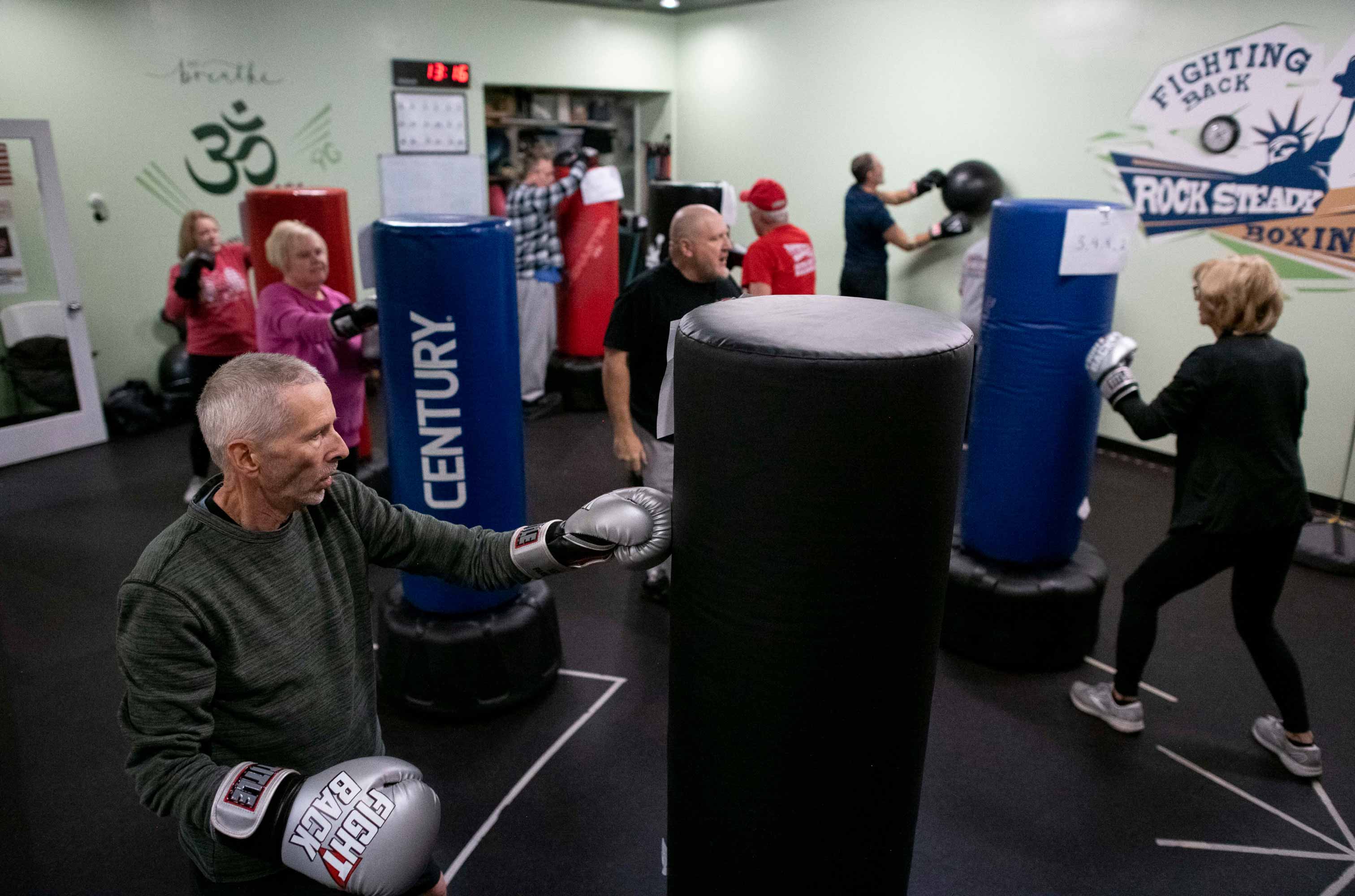 Man in front of a punching bag with boxing gloves on. 