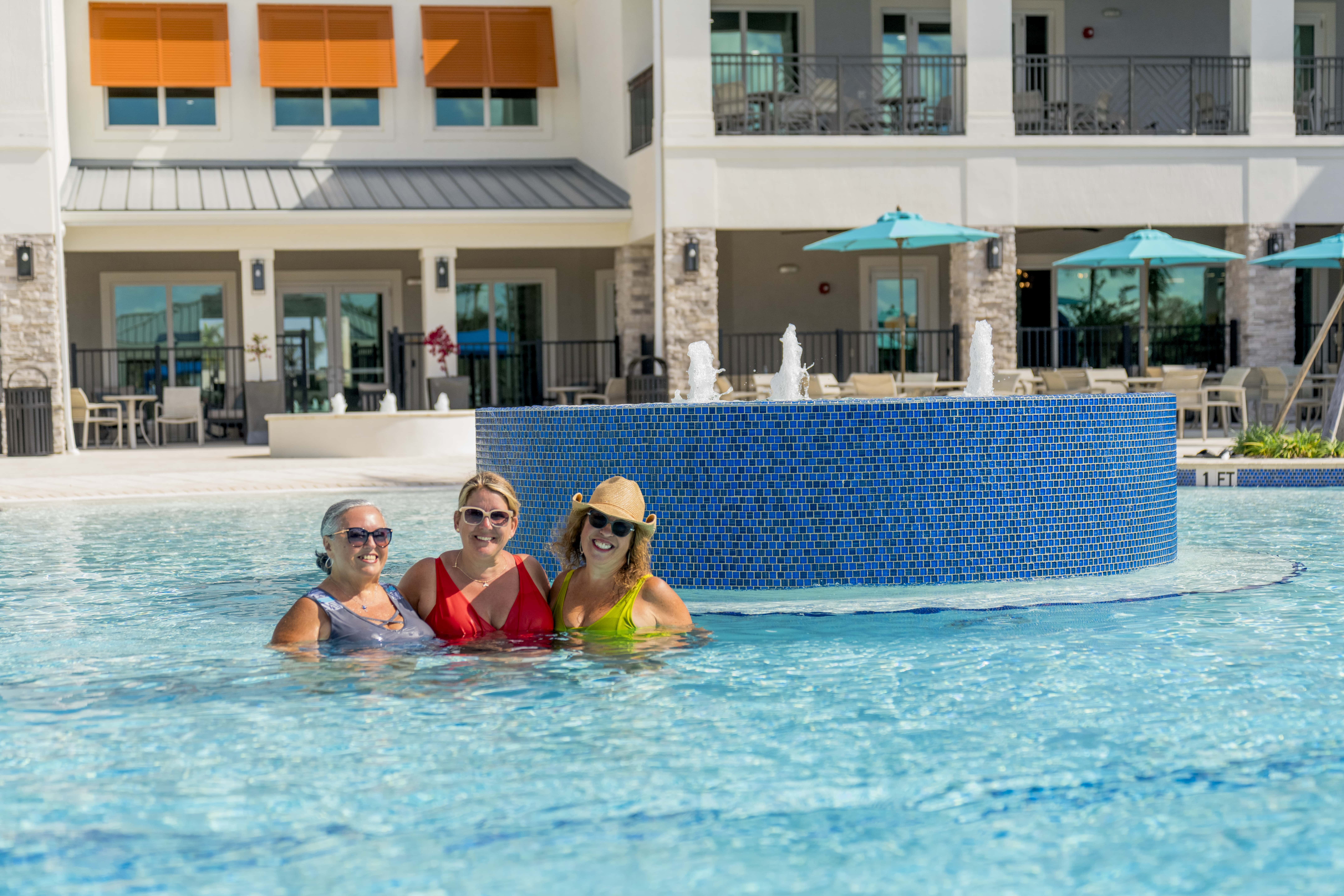Three residents enjoying the resort-style pool at Encore at Tradition