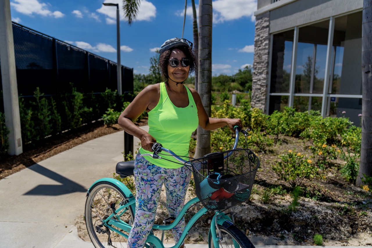 Woman smiling while standing with a bicycle outside Encore at Tradition