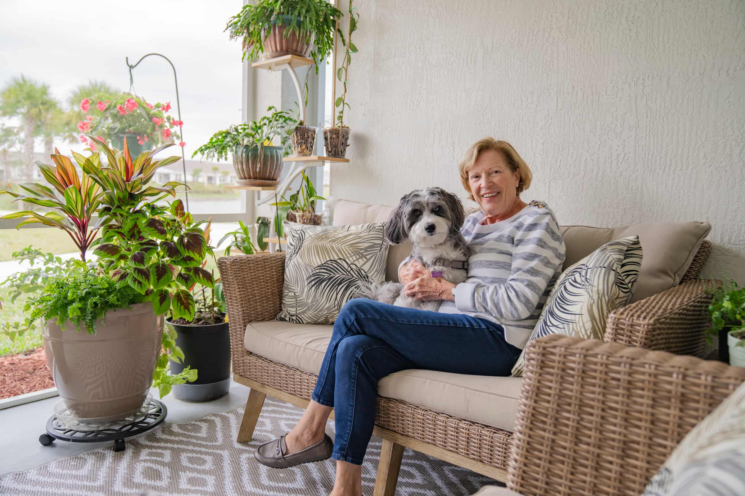 Community member relaxing with her dog outside her apartment at Encore at Tradition in Port St. Lucie, highlighting why many choose Port St. Lucie 55+ communities rentals that are pet-friendly for comfortable living with their pets.