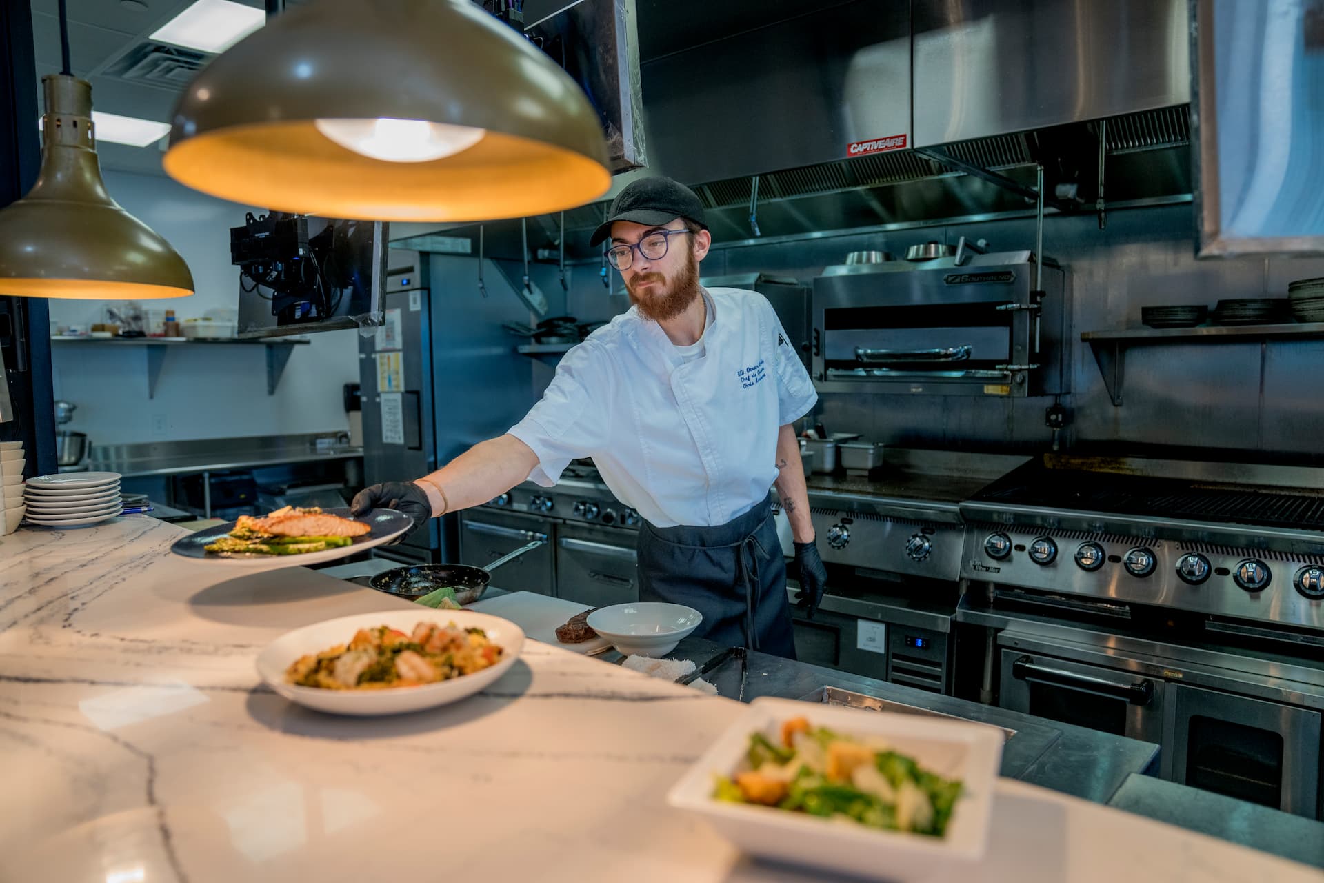 Chef preparing a freshly cooked dish at Blu Ocean Grille, a popular restaurant in Tradition Port St. Lucie known for chef-crafted cuisine and an elevated dining experience.