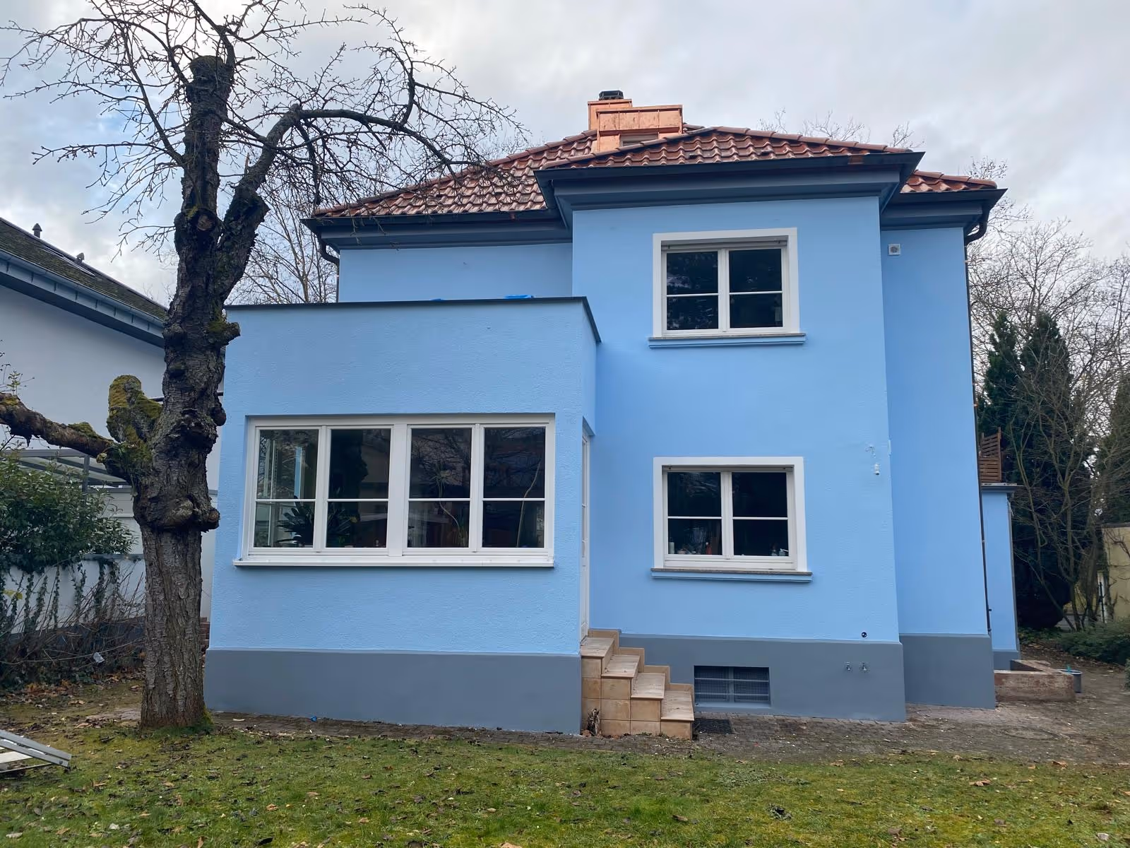 Fassade in frischem Hellblau mit weißen Fenstern und Ziegeldach, ausgeführt vom Malerbetrieb Brückner, Mainz