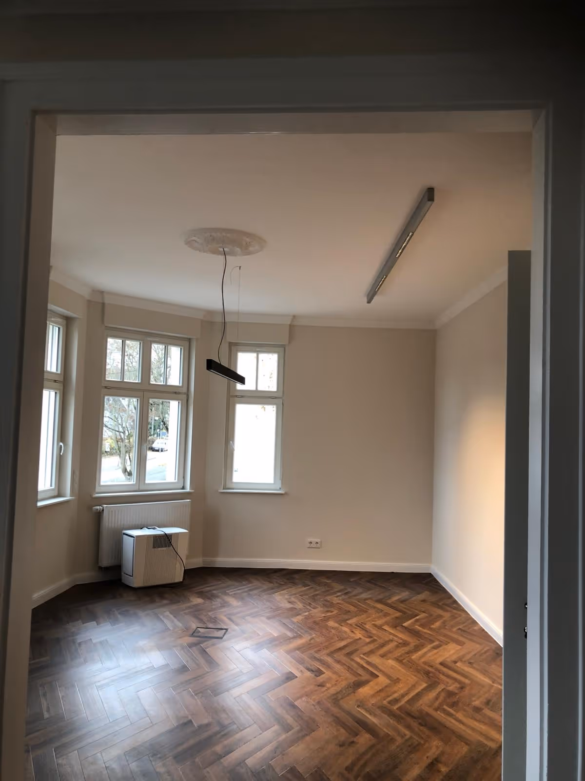 Renoviertes Wohnzimmer mit Fischgrät-Parkett und hellen Wänden in Mainz – Innenausbau vom Malerbetrieb Brückner