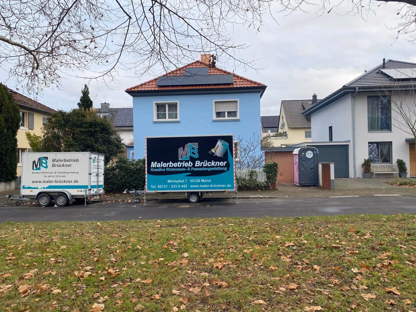 Fassadenanstrich eines Wohnhauses in Mainz mit Werbeanhängern des Malerbetriebs Brückner vor Ort