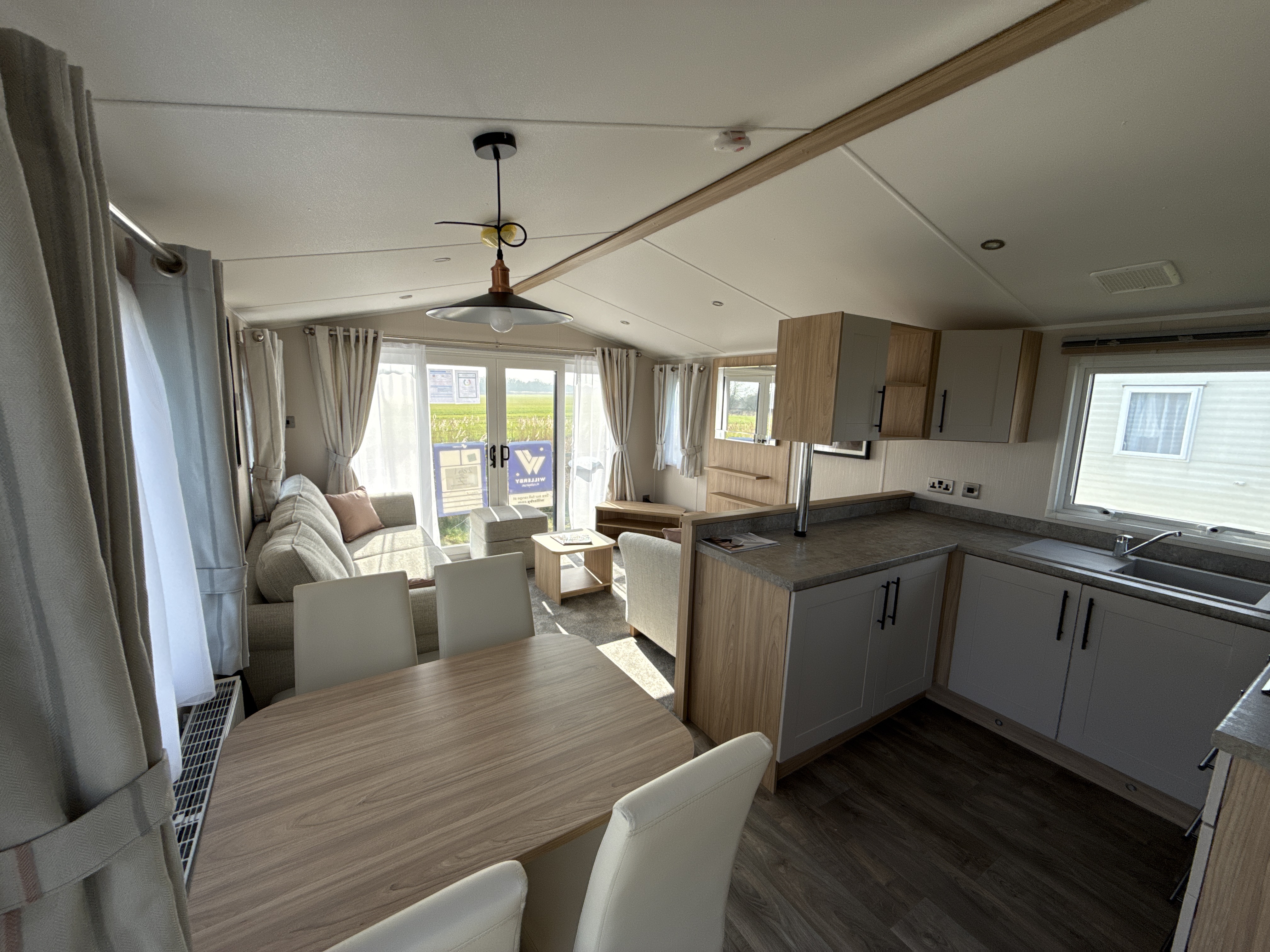Modern mobile home interior with kitchen, dining area, and large windows