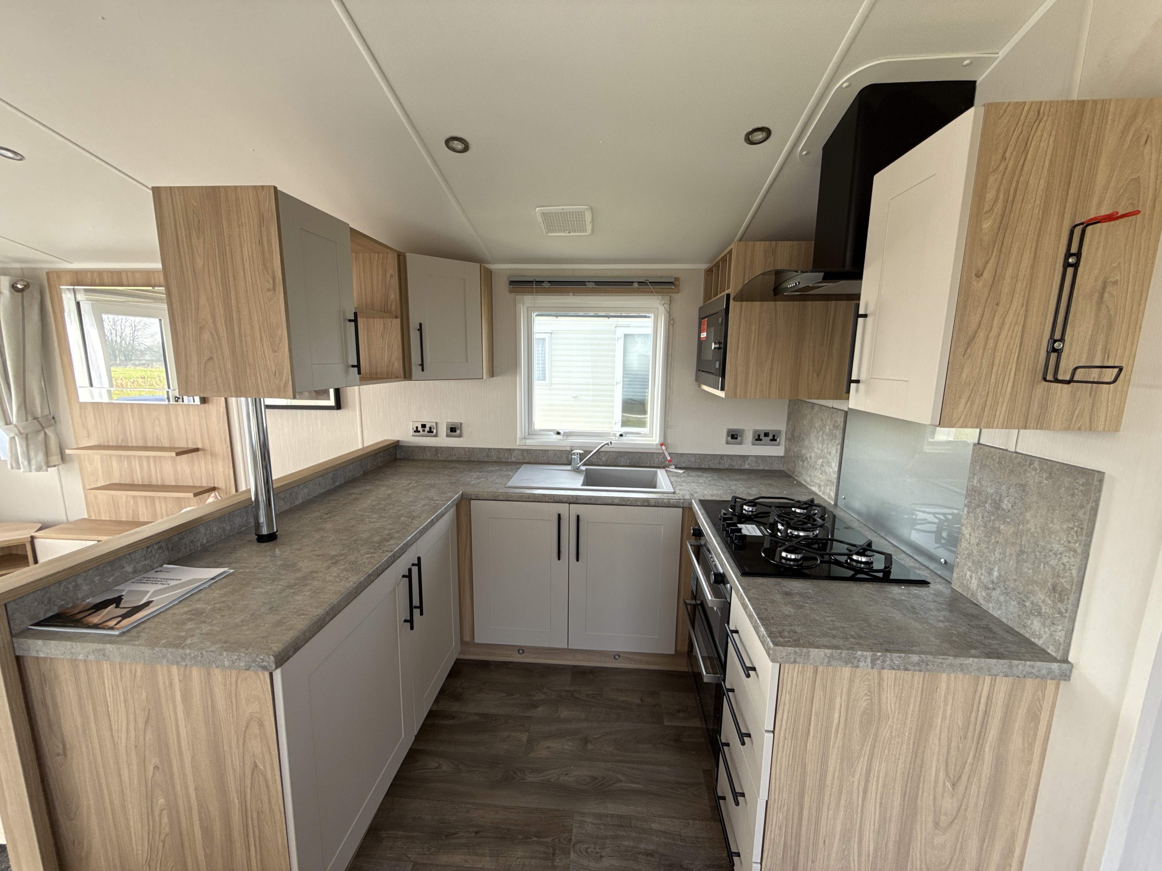 Modern, compact kitchen in a mobile home with wooden and white cabinetry