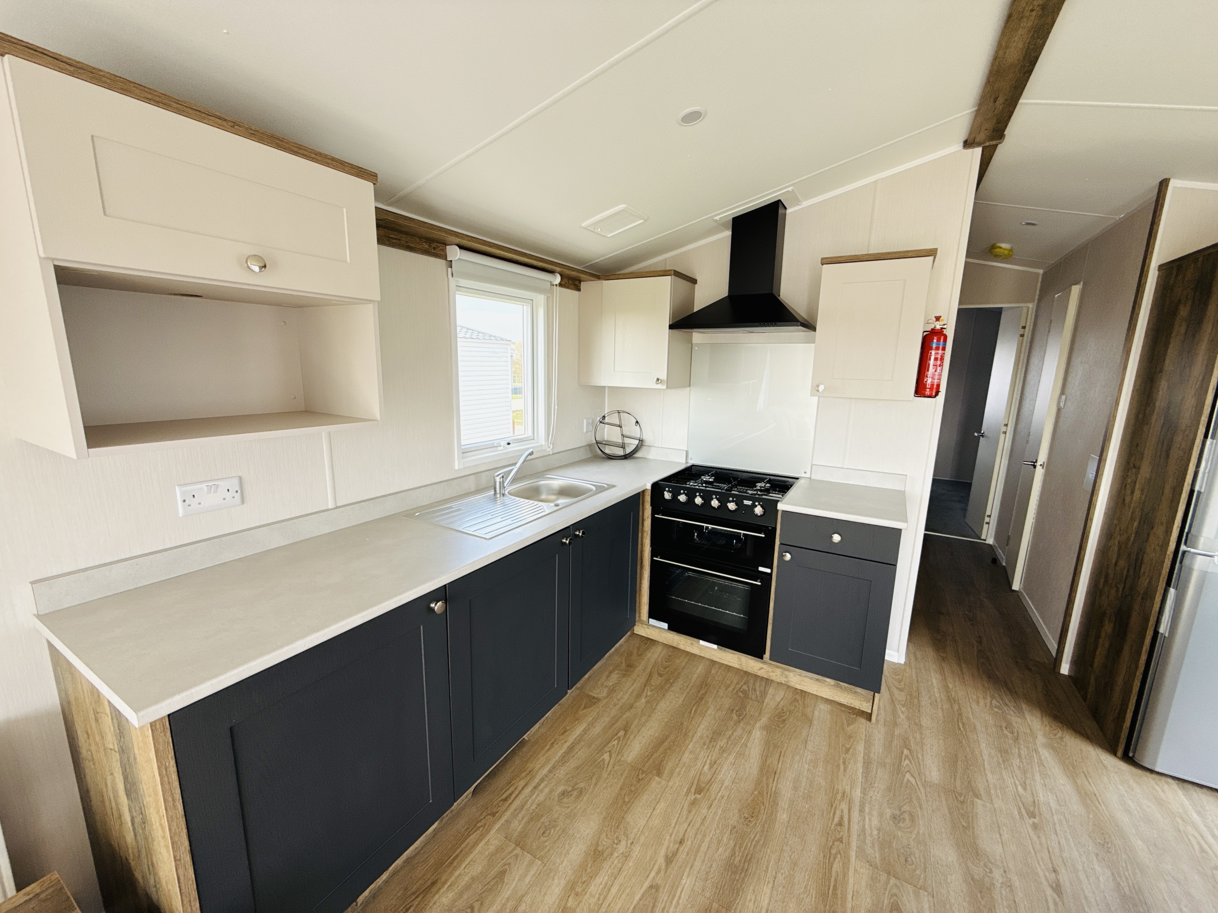 Modern compact kitchen with white and dark blue cabinets and wooden floor