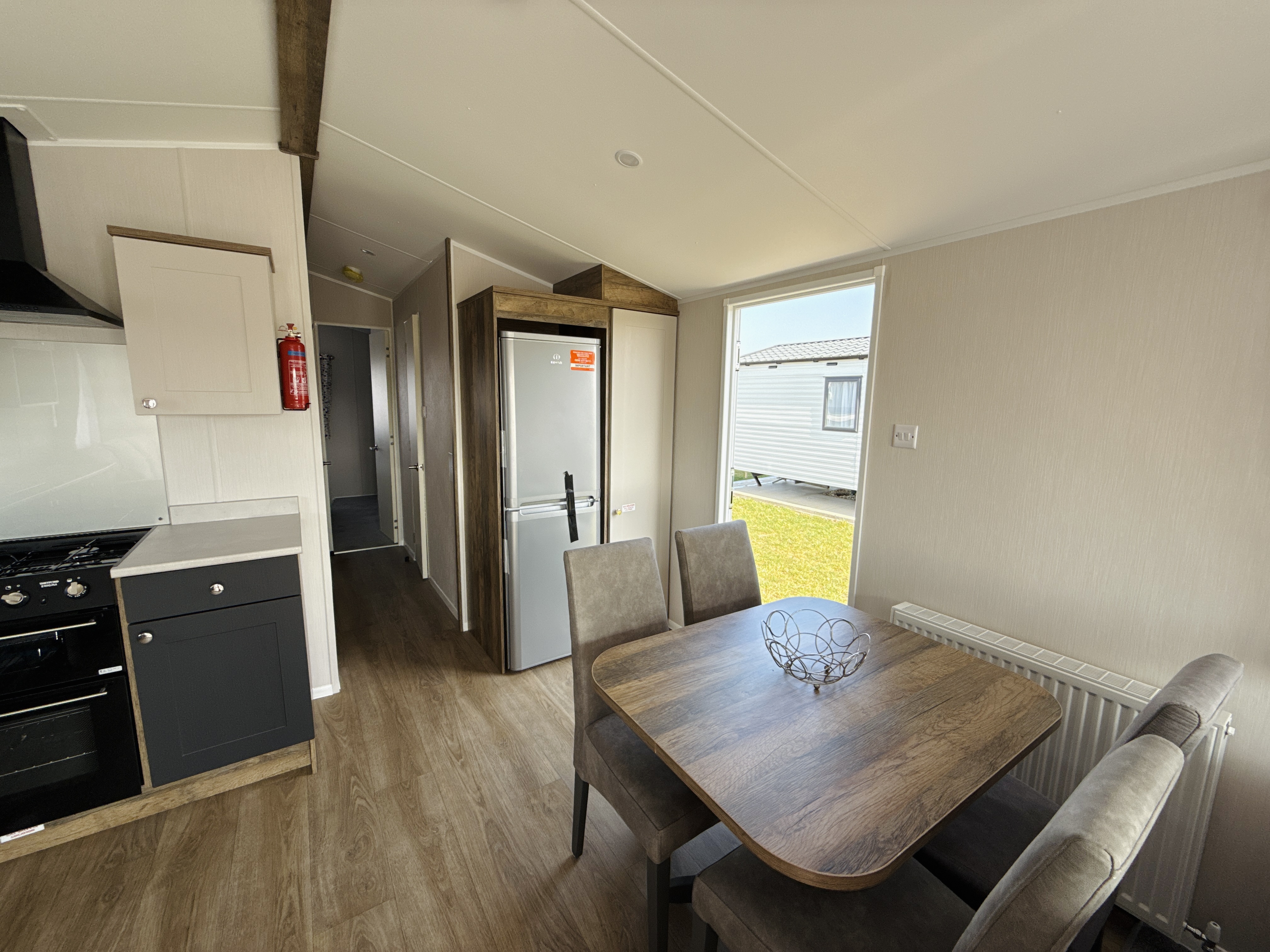 Modern mobile home interior with kitchen, dining area, and wooden floors