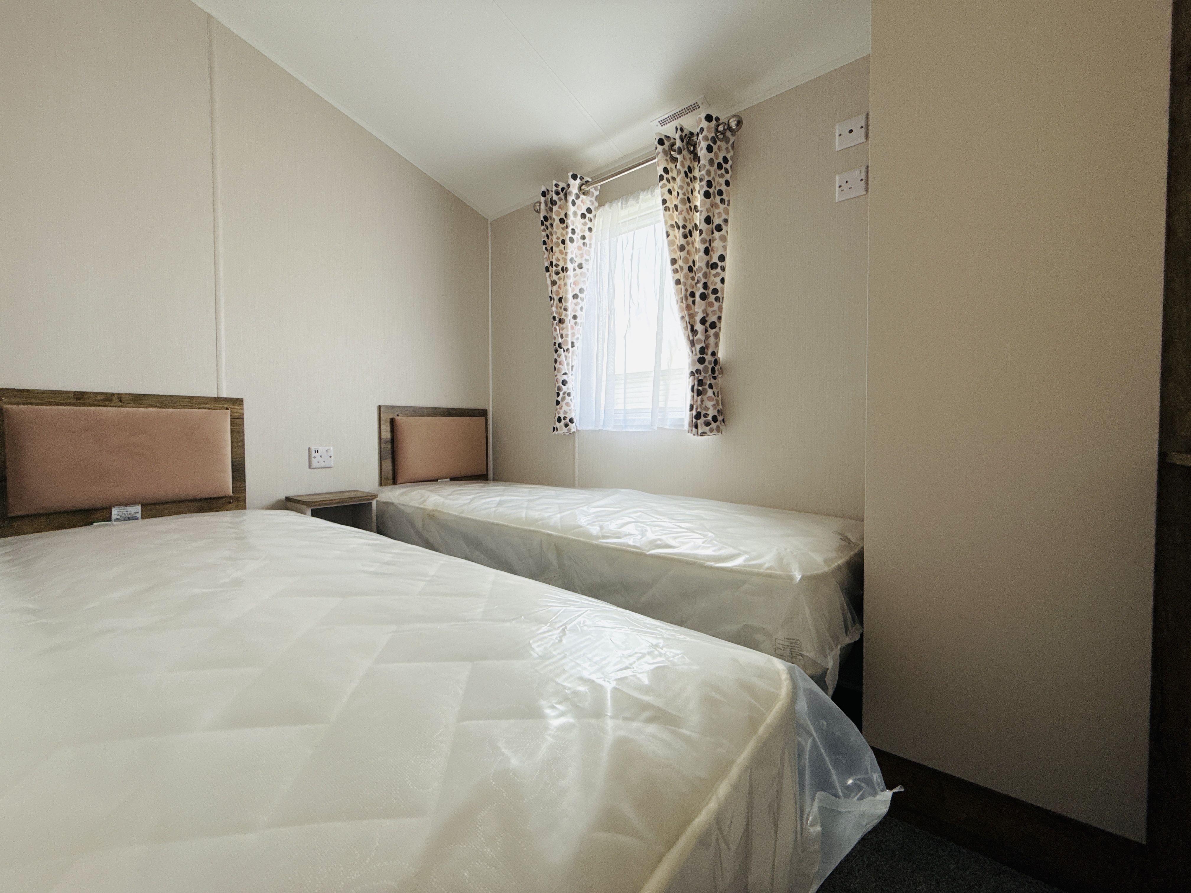Twin beds in a minimalist room with spotty curtains and white walls