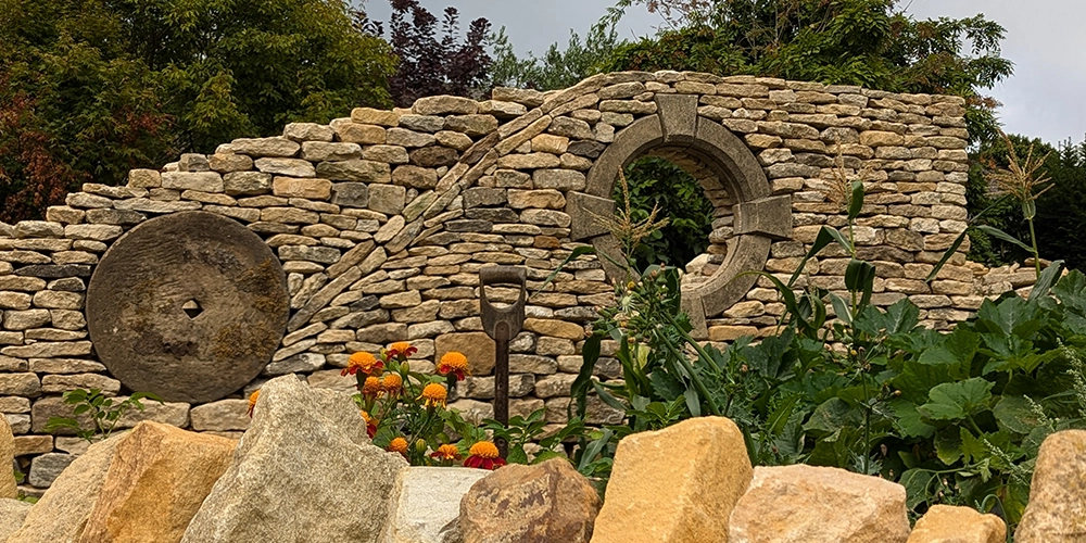 A dry stone wall built from new and reclaimed walling stone with a moongate and millstone feature