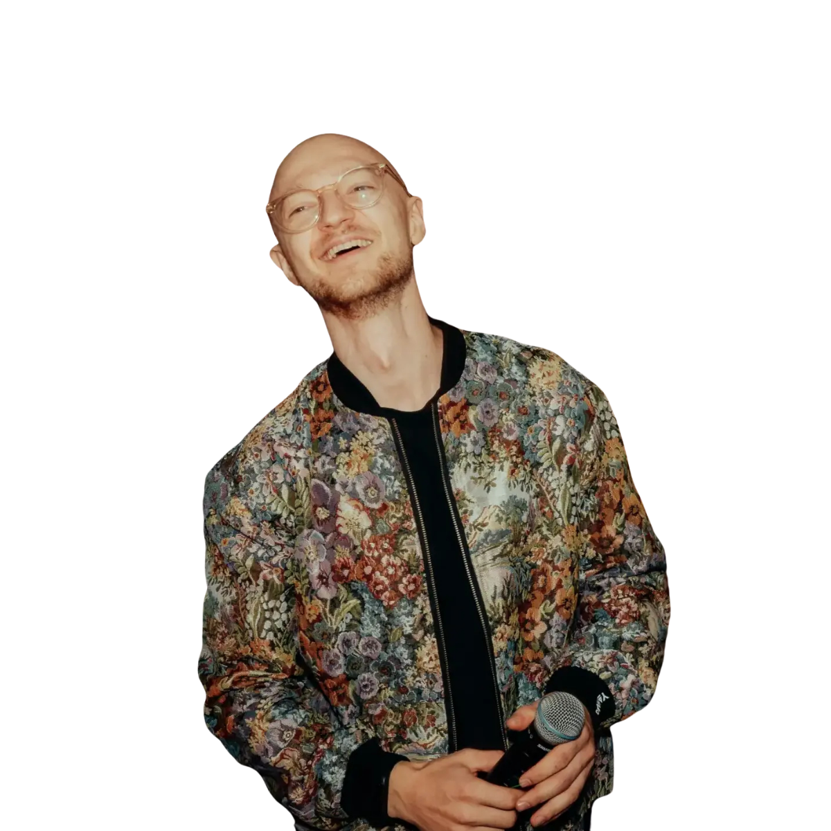 Finn Schüßler Livemusik & DJ wearing glasses and a white cap holds a silver trumpet against a black tiled wall background.