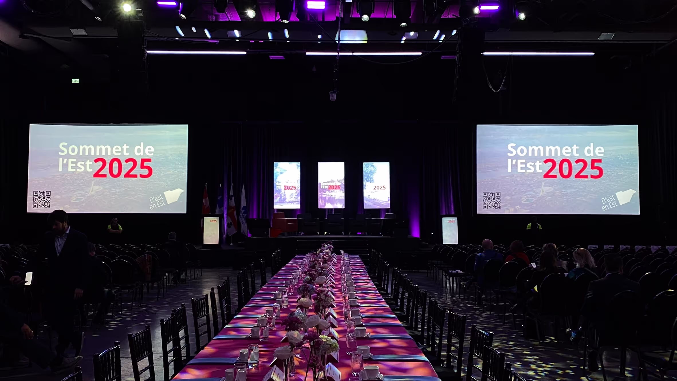 A large room with a purple stage and a large table with a purple tablecloth.