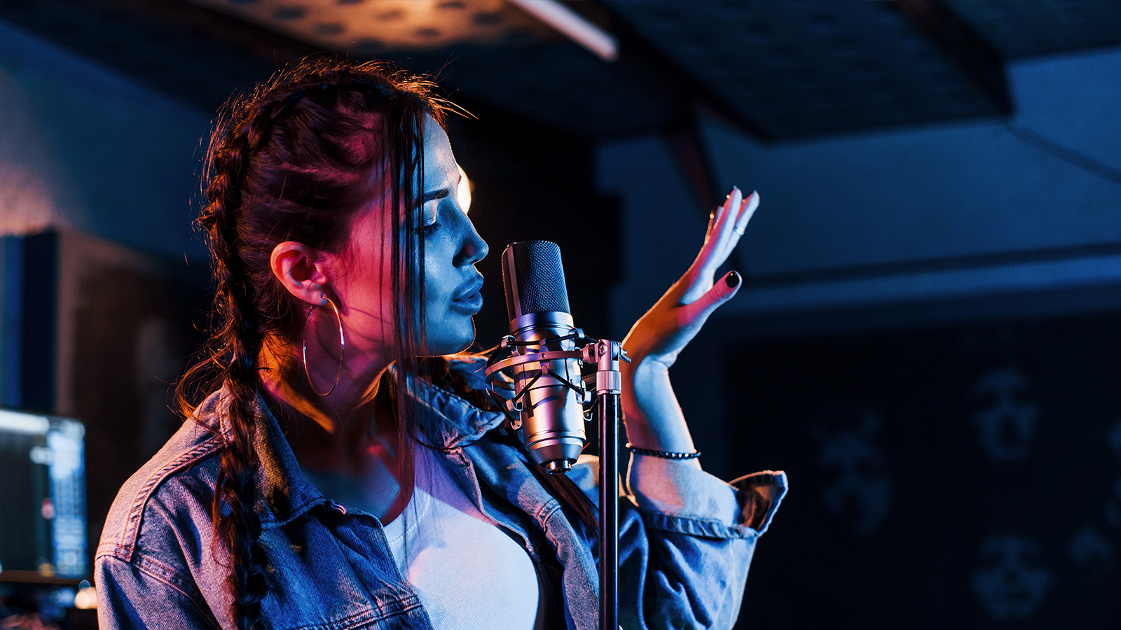 A woman wearing a jean jacket and holding a microphone.