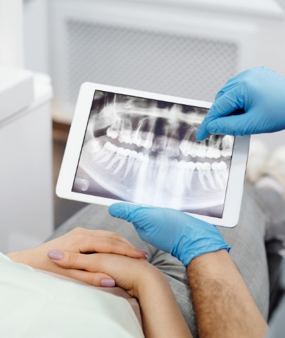 Dental professional reviewing a digital dental X-ray displayed on a tablet