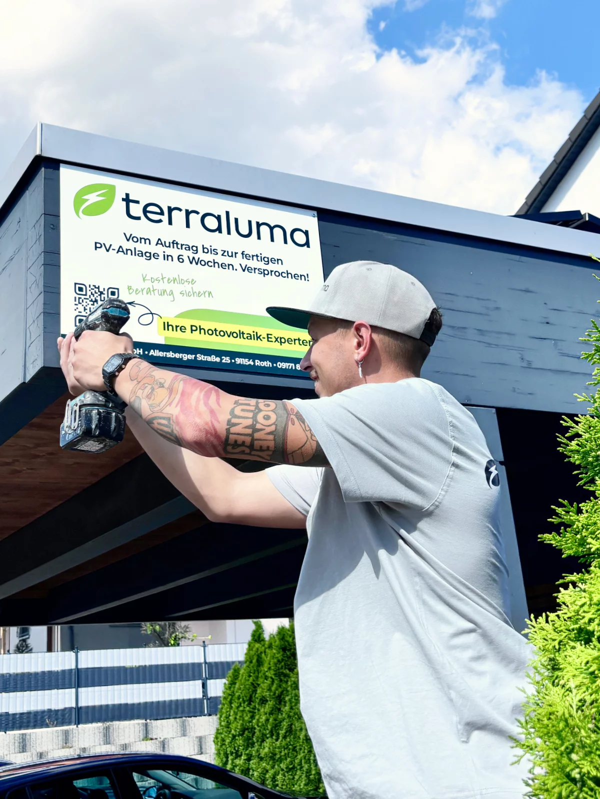 terraluma Mitarbeiter montiert Firmenschild mit Werbetext an Gebäude