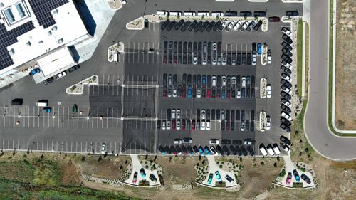 Aerial view of cars parked in outdoor lot under hail netting