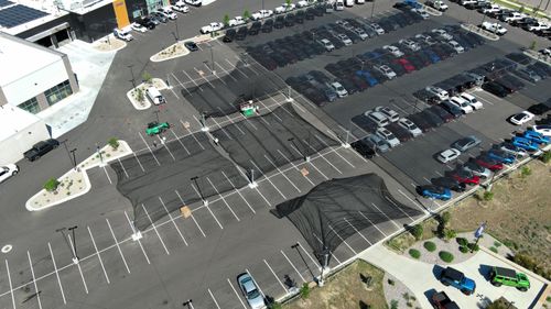 Hail netting being installed over a parking lot of cars, aerial view