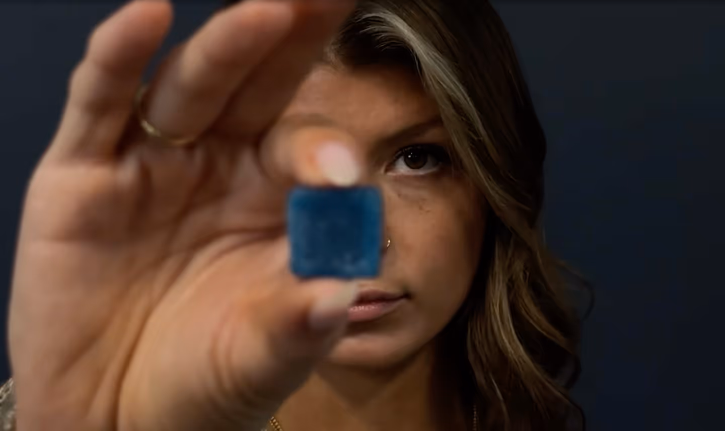 a young woman holding a square blue Chubba Squares Rise gummy in front of her face