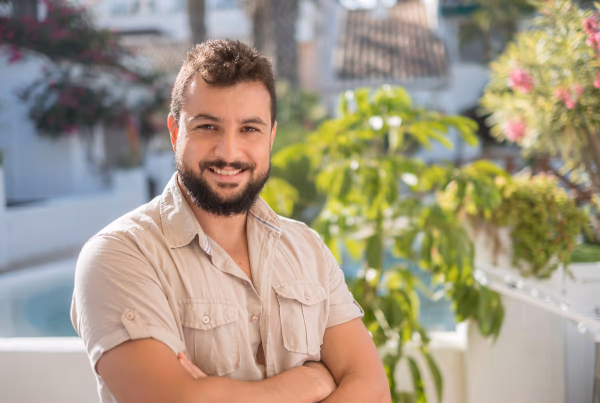 a handsome man smiling and happy with arms crossed