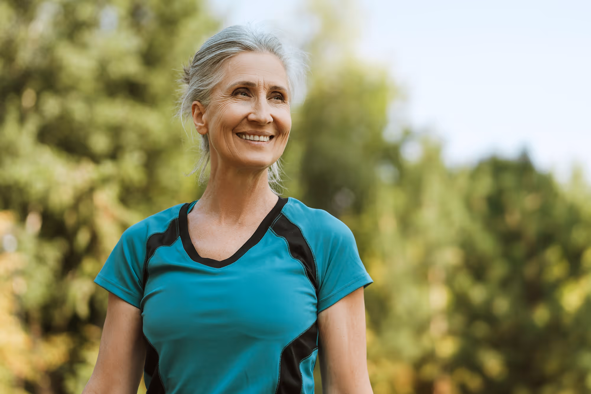 a beautiful fit senior woman with grey hair outside smiling