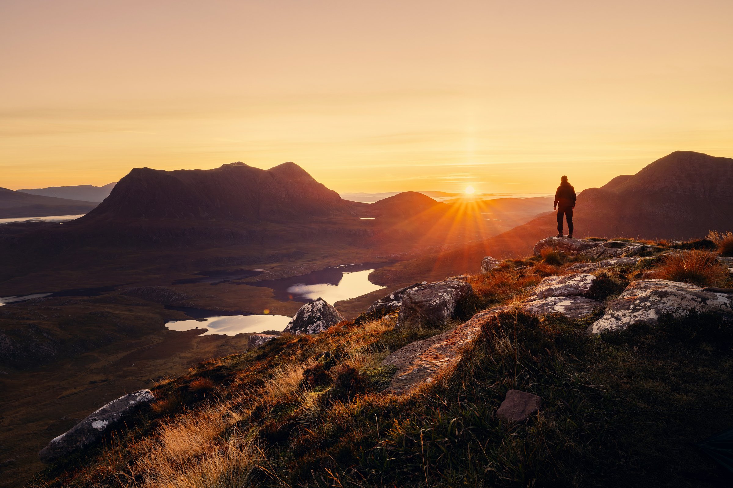 A solitary figure at dawn silhouetted against a vast landscape